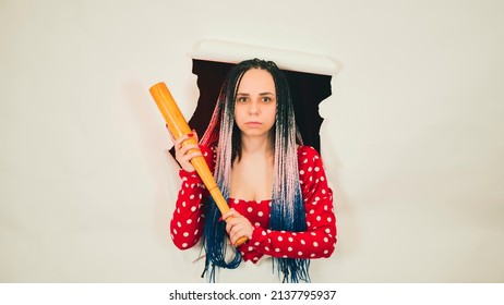 Young woman with baseball bat in hole of white background. Pretty lady with bat