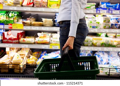 young woman with basket walking in supermarket
