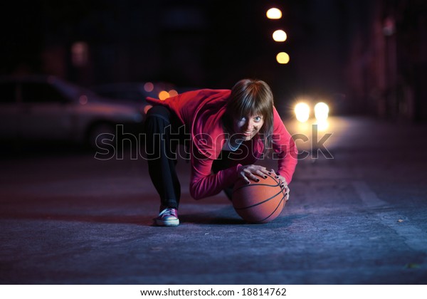 Young woman\
with basketball ball on night\
street