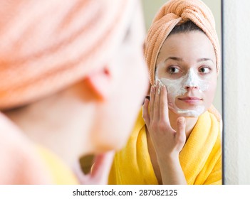 Young Woman In Bathrobe Applying Face Pack Indoors