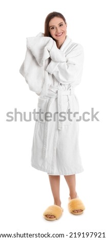 Young woman in bathrobe drying hair with towel on white background