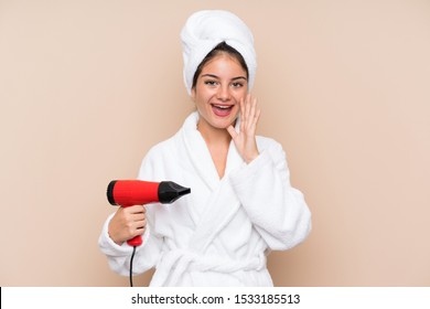 Young Woman In A Bathrobe With Hairdryer Over Isolated Background Shouting With Mouth Wide Open