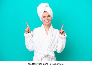 Young woman in a bathrobe isolated on blue background pointing up a great idea