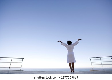 Young woman in bathrobe standing outdoors on balcony - Powered by Shutterstock