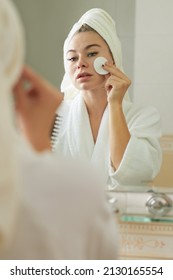 Young Woman In Bathrobe Wiping Face With Cotton Pad Soaked In Toner To Restore Skins PH Level