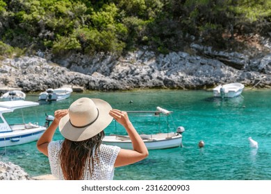 Young woman in beach clothes and sun hat near idyllic cove with boats and turquoise sea at Rasohatica beach on Korcula island in Croatia