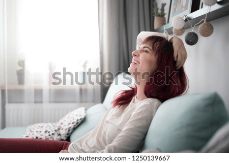Young woman with beaming smile sitting on sofa at home in bright living room