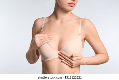 Young woman with beautiful breast on light background