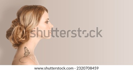 Young woman with beautiful butterfly tattoo on beige background, side view. Banner design with space for text