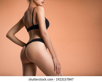 Young  woman with beautiful buttocks. Rear view of a perfect female body. Slim girl in black lingerie posing at the studio. Back view of a female butt.