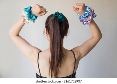 Young woman with beautiful hair clips on grey background. Silk elastic bands on woman's arm. Luxury colors.