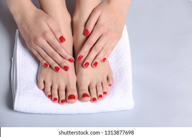 Young woman with beautiful pedicure and manicure on light background