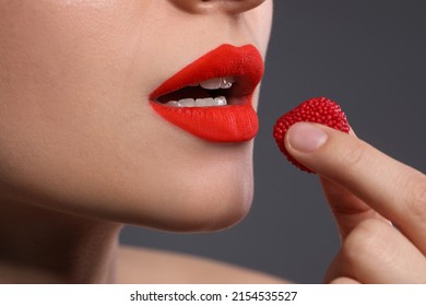 Young Woman With Beautiful Red Lips Makeup Eating Candy On Grey Background, Closeup