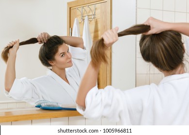 Young Woman With A Beautiful Strong Hair Looking Into The Mirror