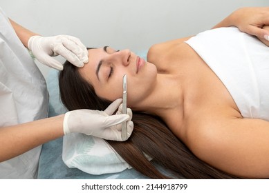 young woman in a beauty center performing a beauty treatment for the skin of the face with the dermaplaning technique - Shutterstock ID 2144918799