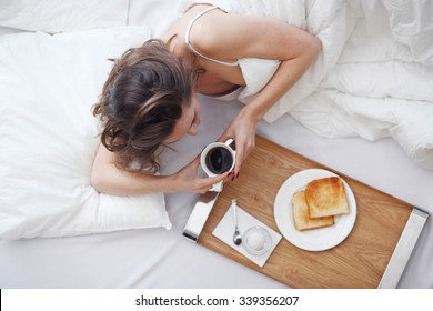 Young Woman In Bed Eating Breakfast