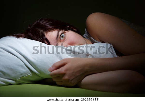 Young woman in bed  eyes opened suffering\
insomnia. Nightmare\
issues