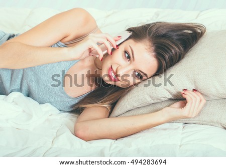 Young woman in bedroom with mobile phone in bedroom 
