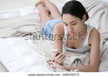 Young woman in bedroom with mobile phone home