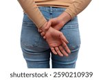 A young woman in a beige top and blue jeans standing with her hands clasped behind her back.
