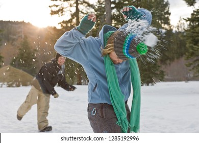 Young Woman Being Hit From Behind By A Snow Ball While Standing In A Snowy Field.