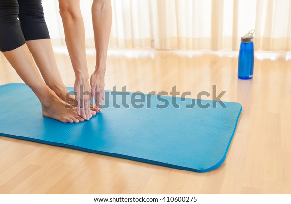 Young woman bending\
down to touch her toes