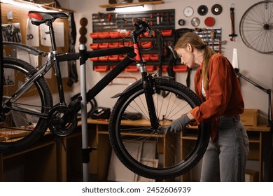 Young woman bicycle engineer or mechanic is repairing a bike in the workshop. Copy space - Powered by Shutterstock