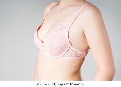 Young Woman In Too Big Pink Push Up Bra On Gray Background, Decollete Care Concept, Perfect Female Breast