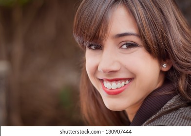Young woman with a big smile looking at the camera on a brown coffee background
