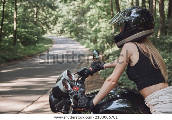 Young woman biker in a helmet sitting on a\
motorcycle in the underground parking\
garage