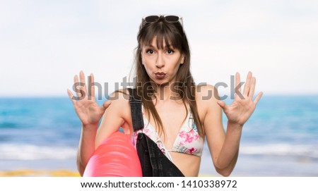 Young woman in bikini counting ten with fingers at the beach
