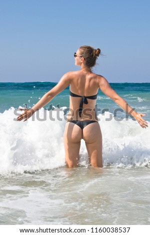 Young woman in bikini enjoying waves in the sea