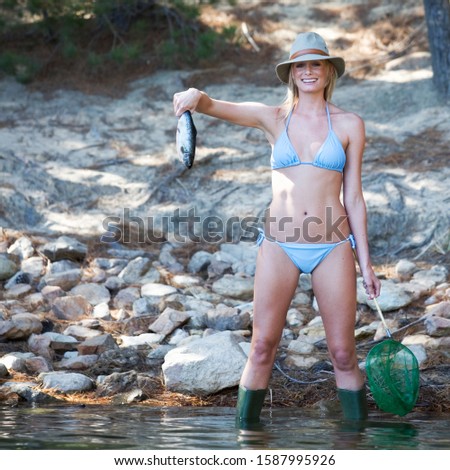 A young woman in a bikini holding a fish