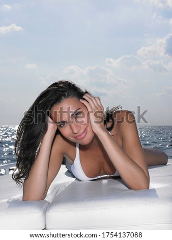 Young woman in bikini lying on cushions on yacht