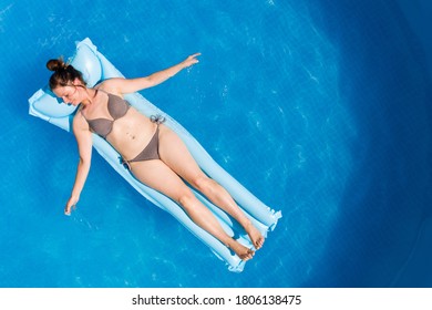 Young Woman In Bikini On Air Mat Mattress In Round Above Ground Swiming Pool. Top View. Vacations At Home Concept.