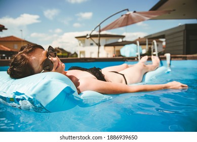 Young Woman In Bikini On Float Mattress In Round Above Ground Swiming Pool In Backyard