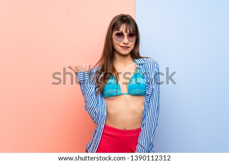 Young woman in bikini pointing to the side to present a product