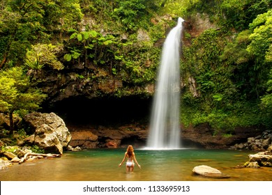 Young woman in bikini standing by Lower Tavoro Waterfalls in Bouma National Heritage Park on Taveuni Island, Fiji. Taveuni is the third largest island in Fiji.
