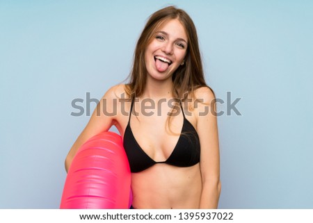 Young woman in bikini in summer holidays showing tongue at the camera having funny look