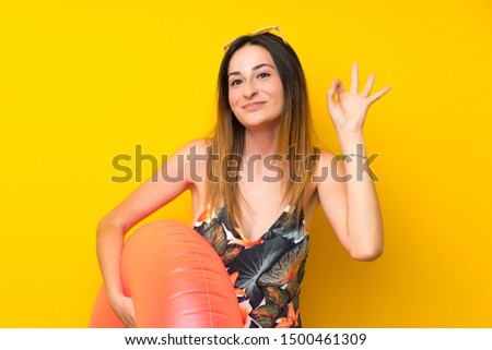 Young woman in bikini in summer holidays showing ok sign with fingers