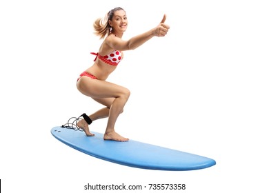 Young woman in a bikini surfing and making a thumb up gesture isolated on white background - Powered by Shutterstock