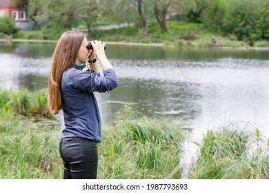 Young woman birdwatcher looking for the birds on the river or lake. Image with copy space
