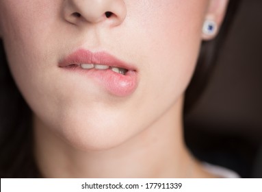 Young woman bites her lips closeup.