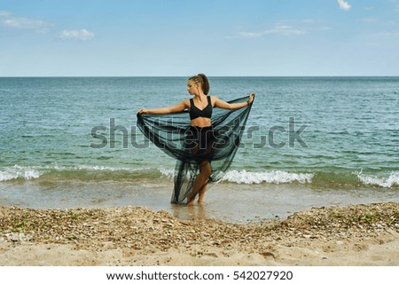 young woman in a black chiffon dress on the seashore