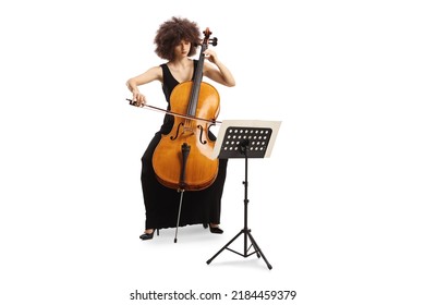 Young Woman In A Black Dress Playing Cello And Reading From A Music Paper On A Stand Isolated On White Background