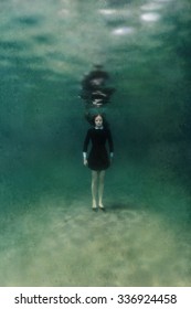 Young Woman In Black Dress Standing On Sand Underwater