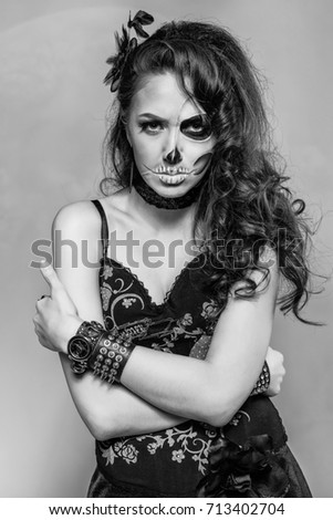 Young woman in black with half face skull make-up.