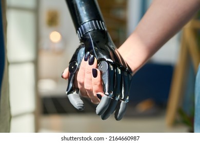 Young woman with black nail polish on her fingernails holding by myoelectric hand belonging to person with physical disability