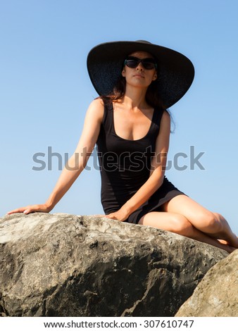 Young woman in black on the sea beach