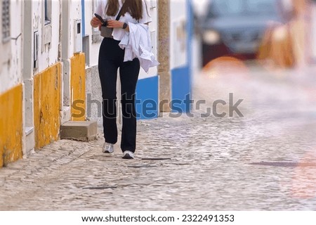 The young woman in black pants walking on a cobblestone street
